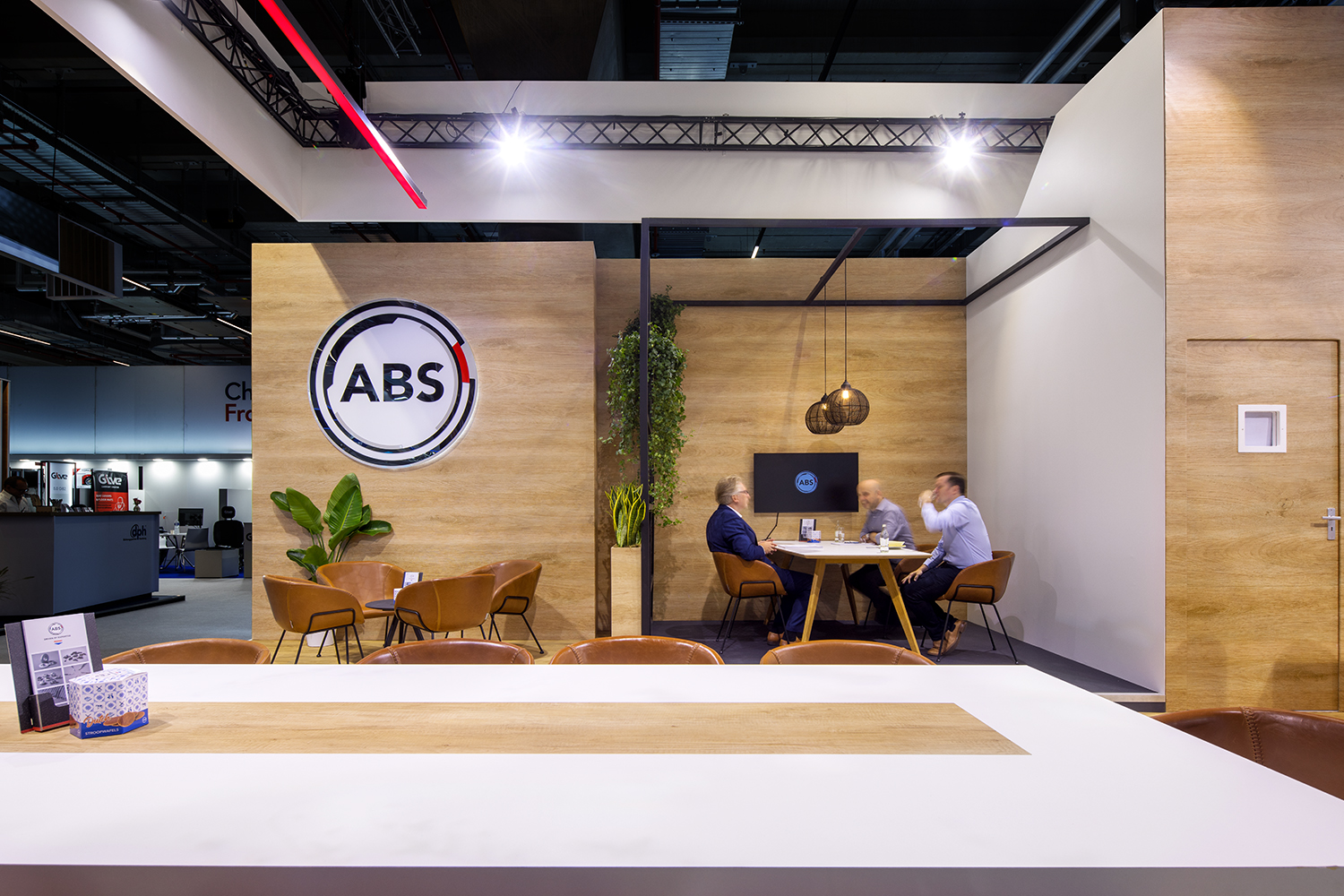 Meetingruimte in de ABS stand op Automechanika met hout, groen en leren zitmeubilair